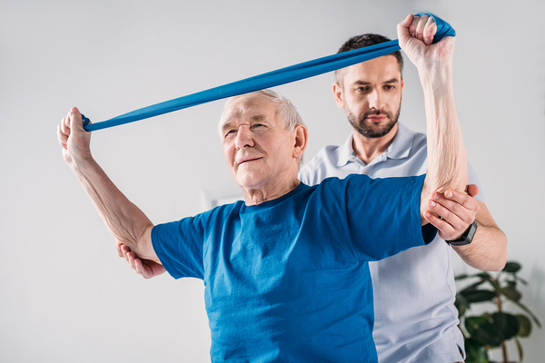 Older gentleman working with exercise bands with a physical therapist.