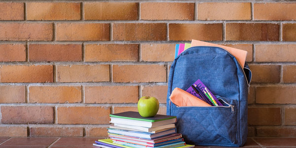 OT Brickwall with books piled up and a backpack.