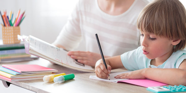 Woman working with a child at a desk.