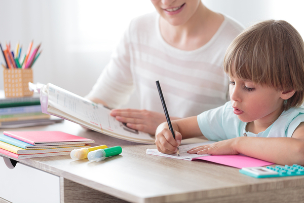 Woman working with a child at a desk.